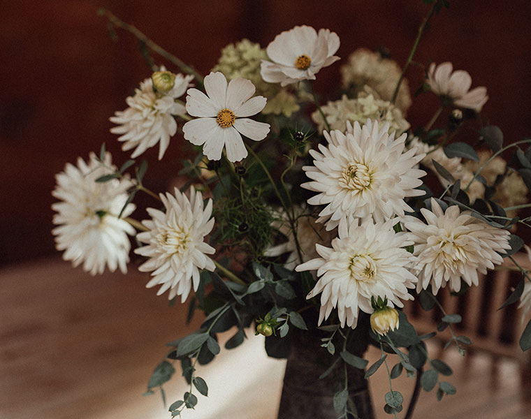 Wedding table flowers with white daisies and foliage in a glass vase