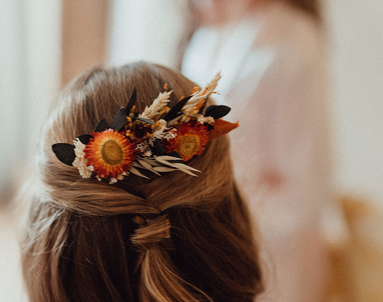 Flower crown with orange blooms and wheat in a child’s hair for an autumn wedding