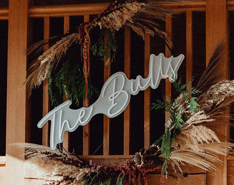 Wedding sign framed by an autumn wreath of greenery, dried grasses, and flowers