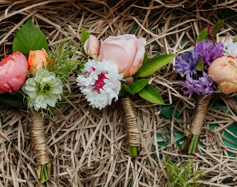 Small floral arrangement of roses, lavender, and wildflowers on a wicker backdrop