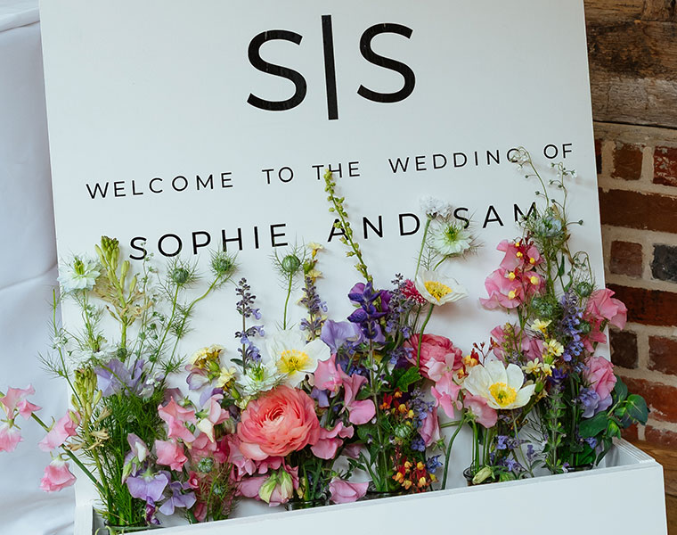 Wedding welcome sign for Sophie and Sam, decorated with a bright floral display
