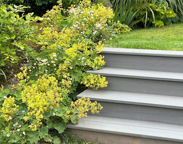 Yellow flowering plants spilling over a modern steel retaining wall