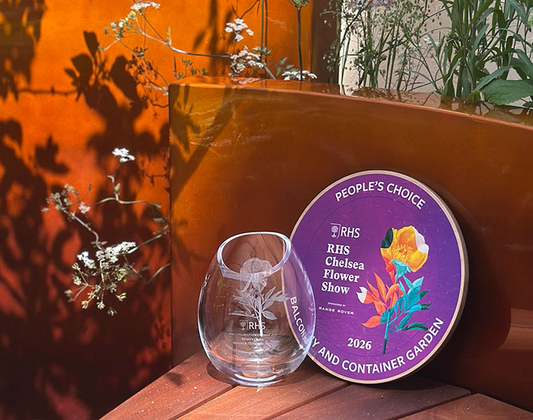 RHS Chelsea Flower Show 2026 People's Choice award plaque and glass trophy on wooden bench.
